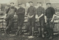 Coopers by barrels displaying their tools, c1900